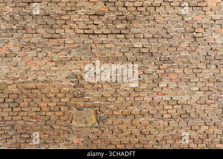 Aged stone and brick wall with uneven surfaces, showcasing rustic character and natural weathering effects Stock Photo