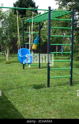 Blue plastic swing in green sunny garden, front view Stock Photo