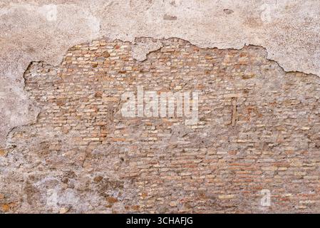Weathered brick wall with cracked plaster, revealing aged surface full of rustic charm and historic character Stock Photo