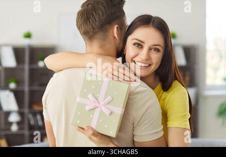 Happy woman congratulating boyfriend with birthday or other special occasion, holding gift box Stock Photo