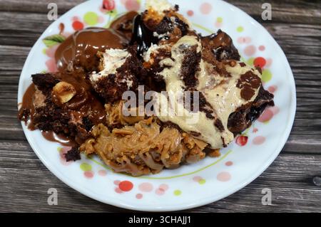Plate of mixed desserts of Tiramisu ladyfinger pastries (Savoiardi) dipped in coffee, Dark chocolate spread profiterole cream puffs, filled French cho Stock Photo