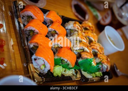 lose-up of assorted sushi rolls with salmon and avocado on a wooden table. Stock Photo