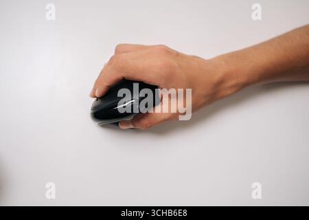 Close-up top view of male hand holding vertical ergonomic mouse on white background, highlighting design and promoting comfortable computer use for Stock Photo