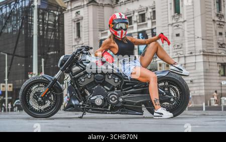 Young woman posing on a custom Harley motorcycle, urban street Stock Photo