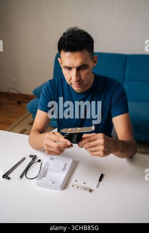 Vertical portrait of skilled technician male assembling wi-fi module using tools at home office desk, focusing on intricate components and ensuring Stock Photo