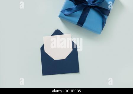Blue gift box, envelope and empty blank on pastel blue background. Flat lay. View from above. Copy space. Happy Fathers Day Stock Photo