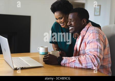 Happy couple sharing laptop at dining table Stock Photo - Alamy