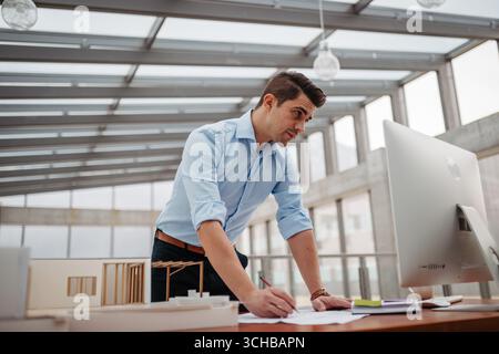 Young businessman, engineer working in office, working on plan or technical document. Stock Photo