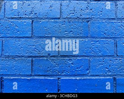 Close-up of a blue-painted brick wall with visible texture and weathering, ideal for backgrounds, design use, or architectural reference. Stock Photo