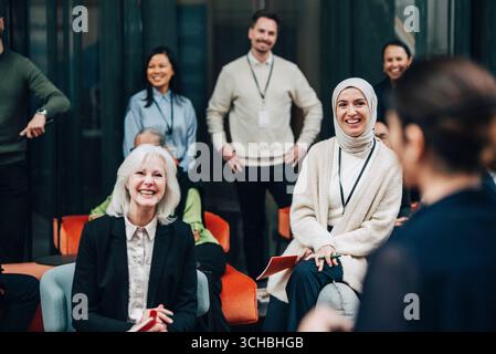 Smiling female business professionals listening to keynote speaker at seminar in convention center Stock Photo