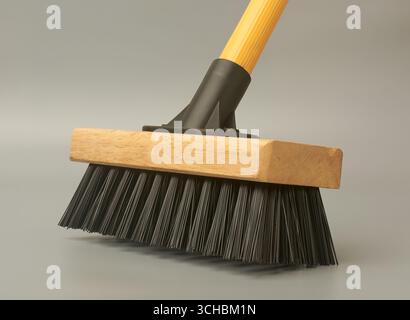 close-up scrub broom or deck brush with wooden head and black bristles isolated gray background, side view Stock Photo