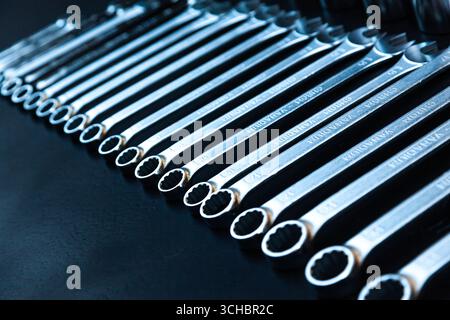 New wrenches are stacked next to each other in a row on a black background. Stock Photo