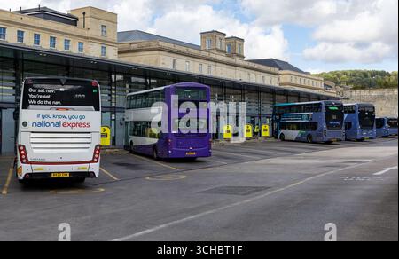 Bath bus station with various buses parked, including National Express and double-decker buses, against a backdrop of historic architecture Stock Photo