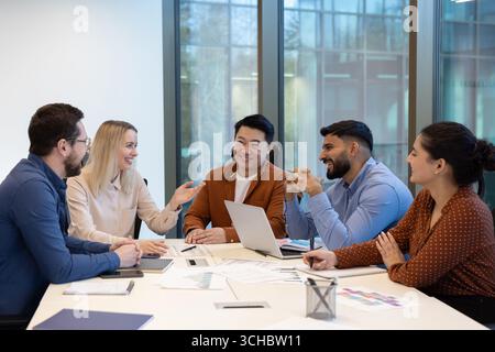 Five smiling business colleagues are enjoying a productive meeting in a bright, modern office, collaborating on a project and sharing ideas Stock Photo