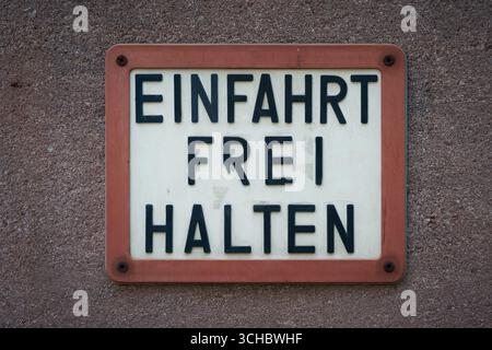Sign on a house wall with the German inscription Einfahrt freihalten. Translation: Keep driveway clear Stock Photo