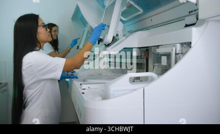Two women scientists operate advanced laboratory equipment while conducting research in a modern lab environment. Stock Photo