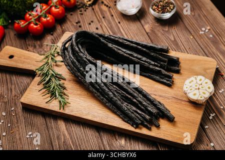 Smoked meat sticks or kabanos and spices on a rustic board, ideal for gourmet food presentations Stock Photo