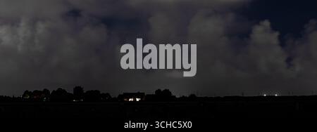Panorama of tall cumulus clouds over the Dutch countryside at night Stock Photo