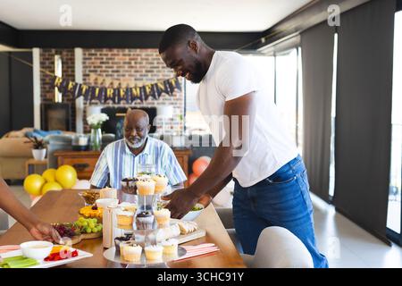 Celebrating retirement at home, adult family sharing cupcakes and decorations, joyful moments. celebration, happiness, party, togetherness Stock Photo