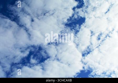 A serene blue sky with fluffy white clouds drifting by Stock Photo