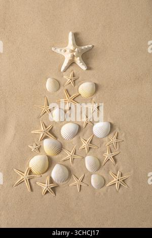 Creative alternative Christmas tree made of seashells and starfish on sandy background. Beach and holiday themes, coastal festive feel. Stock Photo