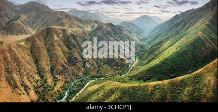 Aerial view of a winding road following the edge of a lush green lake ...
