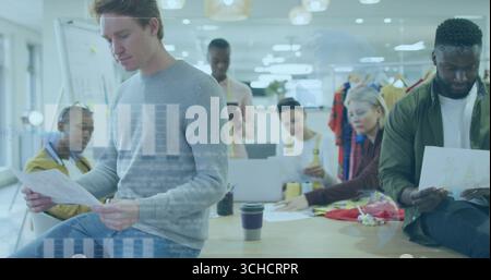 Six professionals collaborating around wooden table in office, with design sheets, fabric swatches. Collaboration, teamwork, creative, fashion, worksp Stock Photo