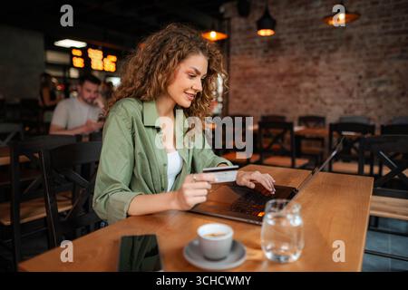 Young woman shopping online using laptop and credit card in cafe Stock Photo