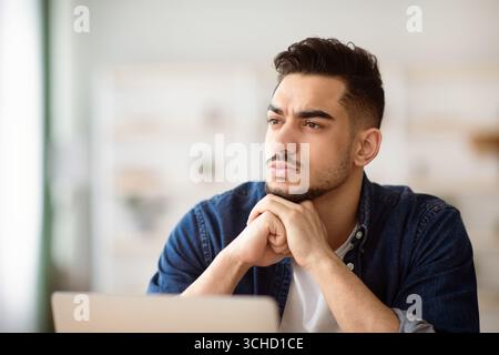 Thoughtful arab man employee working on laptop Stock Photo