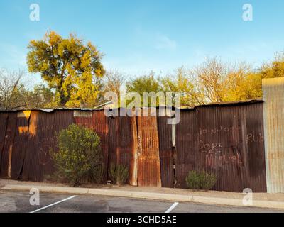 The iconic rusty, weathered corrugated metal fence is handmade, evoking resourcefulness and resilience in the harsh Southwest environment. Stock Photo