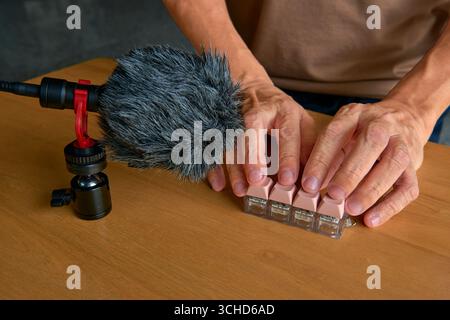 A person's hands typing on a mechanical keyboard in front of a microphone with a windscreen. A concept for ASMR content creation, satisfying sounds, a Stock Photo