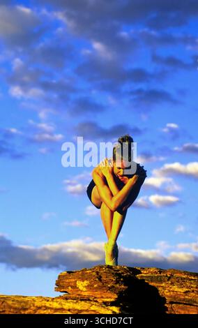 A single female ballerina balances on a rock outcropping at sunset above Sabino Canyon recreation area. Tucson, Arizona Stock Photo