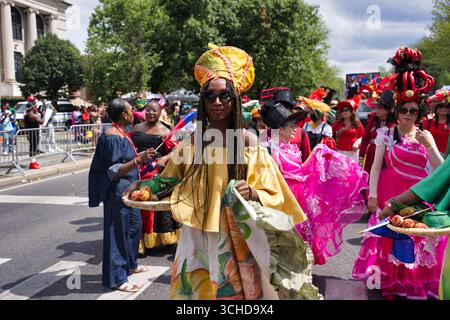 People in vibrant costumes and elaborate hats participate in an outdoor parade. Stock Photo