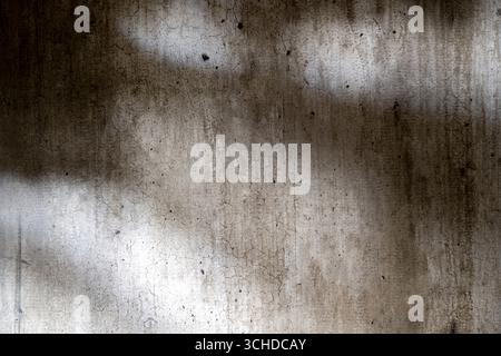 Abstract image of a grungy and aged cement surface. The texture features cracks and a shadow overlay. Copy space. Textured background Stock Photo