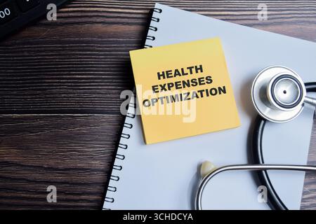 Concept of Health expenses optimization write on sticky notes isolated on Wooden Table. Stock Photo