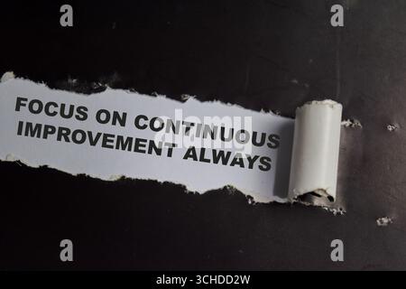 Focus on continuous improvement always Text written in torn paper Stock Photo