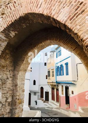 Colorful street framed by a rustic stone arch in Tangier’s historic quarter – 29 Nov 2019.Tangier, Morocco Stock Photo