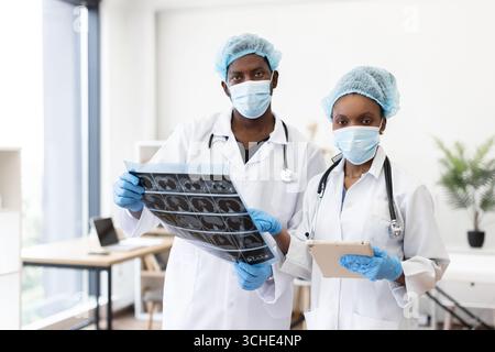 Surgeons discussing medical imagery while wearing protective masks in hospital Stock Photo