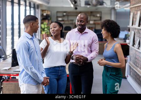 In office, diverse colleagues discussing project, engaging and smiling during meeting Stock Photo