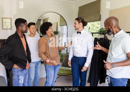 Wedding suits, male group discussing suit fitting in modern fitting room, with measuring tape Stock Photo