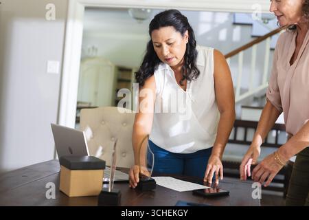Senior women organizing documents and awards on table in home office setting Stock Photo