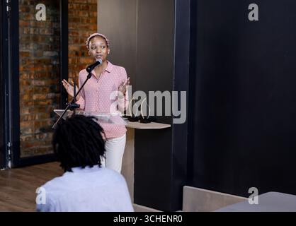 At office, african american woman speaking at podium during business presentation, copy space Stock Photo