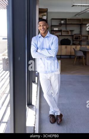 Confident man in office wearing semi-formal attire, smiling by large window, copy space Stock Photo