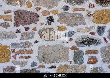 Floor gravel pebble stone on concrete wall background or fence texture made of a close up of medieval stone walls with colorful pebbles. Abstract pebb Stock Photo