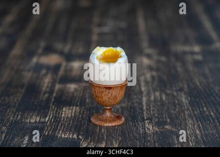 Soft boiled egg in eggcup on wooden table background, close up Stock Photo