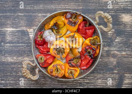 Baked red and yellow bell peppers. Peppers in a baking dish on a wooden table. A healthy and delicious vegetarian dish. Close up, top view Stock Photo