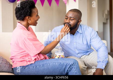 At party, Couple enjoying sweet treats together at home, sharing joyful moments Stock Photo
