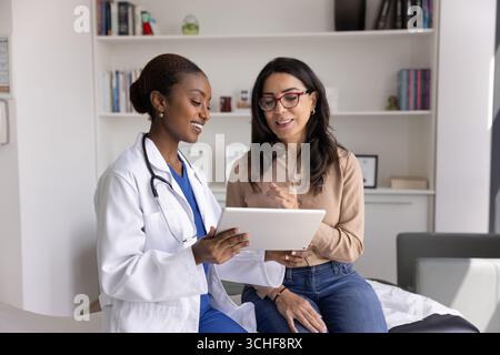 African female doctor and her older woman patient using tablet Stock Photo