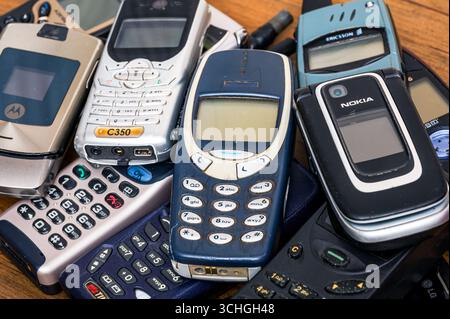 Milan, Lombardy, Italy - February 25, 2025: Old Nokia, Ericsson and Motorola cell phones stacked on a wooden table represent a milestone in the histor Stock Photo