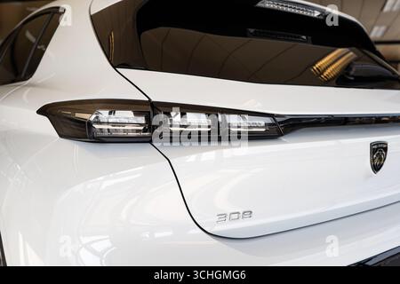 Safenwil, Switzerland, August 16, 2025. New Peugeot 308 compact car rear tail light close up view. Emil Frey open days showroom floor, wide angle view Stock Photo